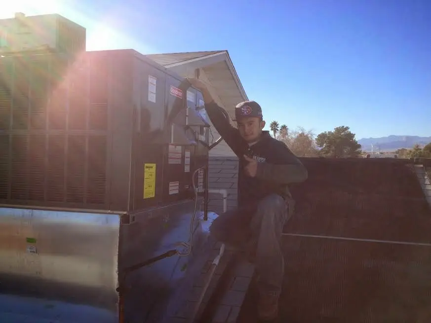 HVAC technician performing AC Tune-Up on a rooftop unit in Marengo